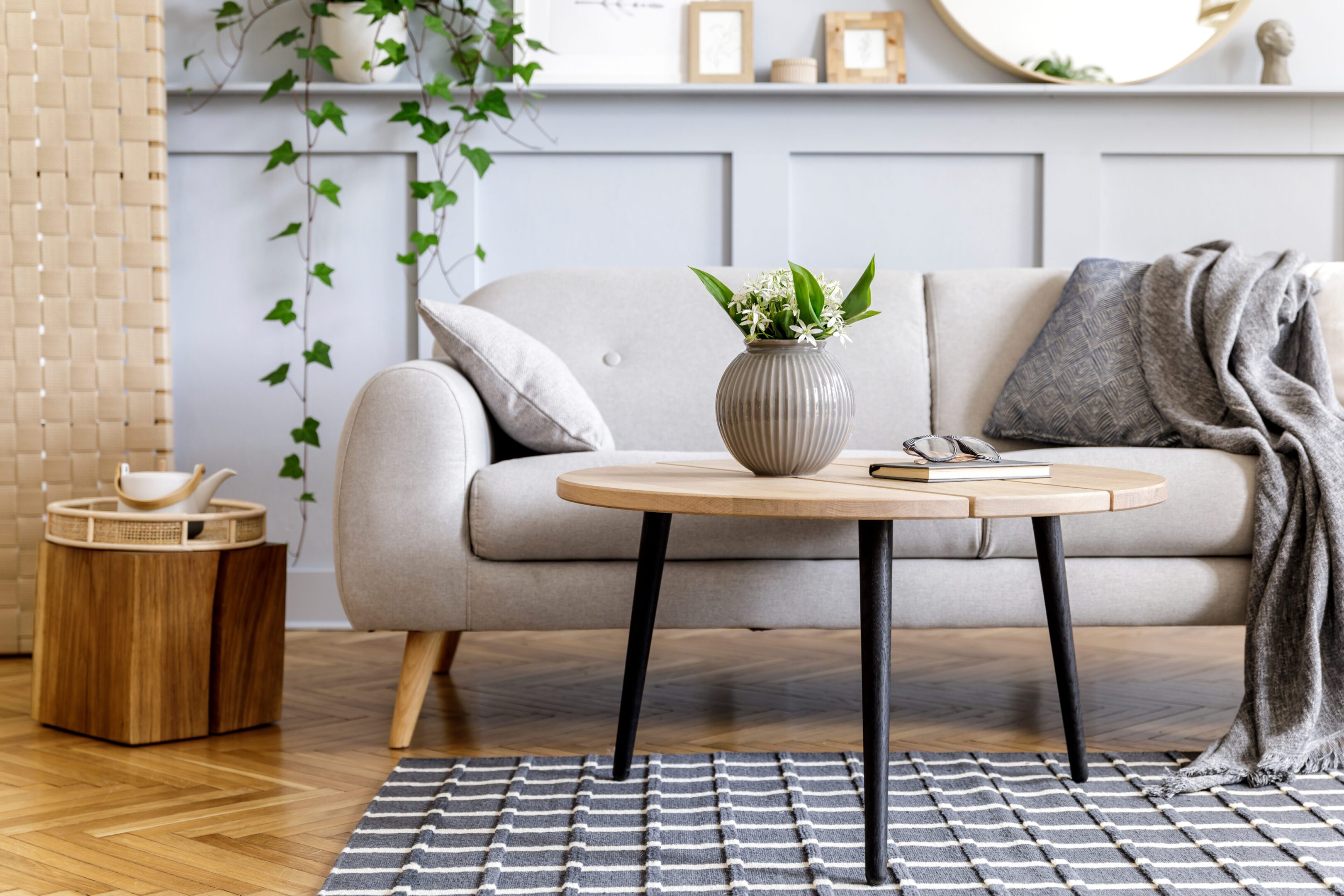 Stylish scandinavian living room interior with design sofa, furniture, tropical plants and decoration. Grey wall. Neutral concept. Template.
